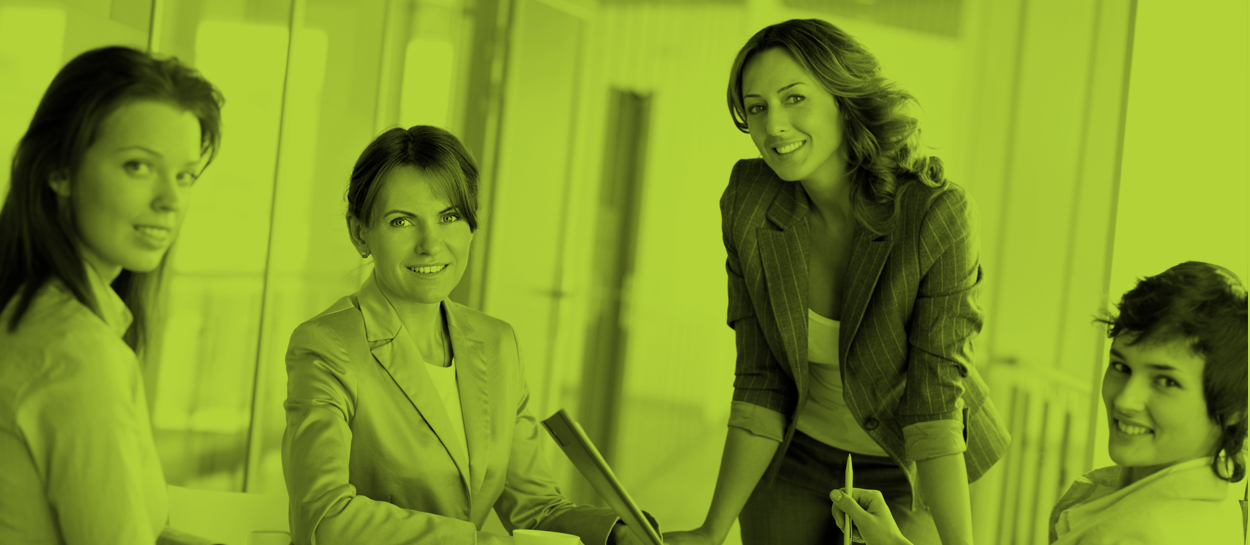 Four women-friendly professionals in business attire in a meeting room, discussing and smiling, in a monochromatic green filter.