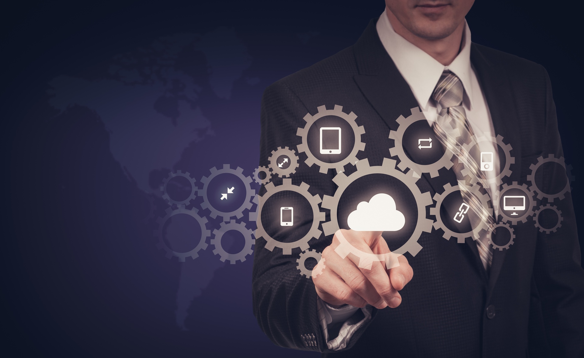 A man in a suit touches a digital cloud icon surrounded by interconnected gear icons representing various technology functions, with a world map in the background.