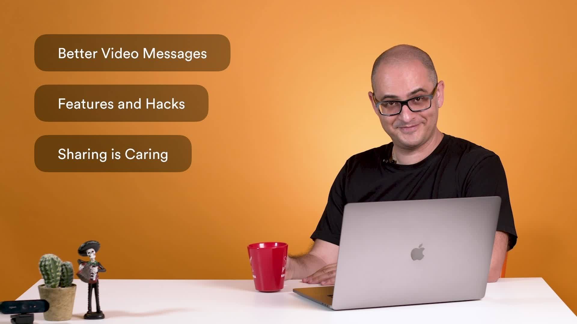 A person with glasses and a red mug smiles while sitting at a table with a laptop. Text on the image reads: "Better Video Messages," "Features and Hacks," and "Sharing is Caring.