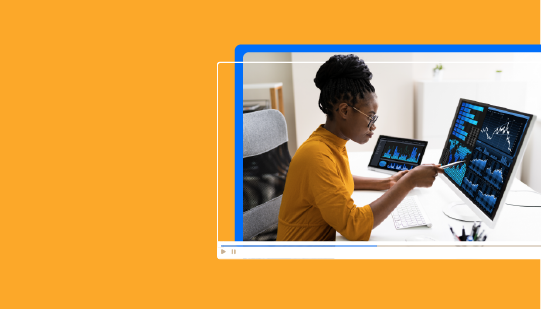 Person in an orange shirt using a stylus on a computer screen displaying data charts, with a tablet showing similar data. A faint blue border and orange background are visible.