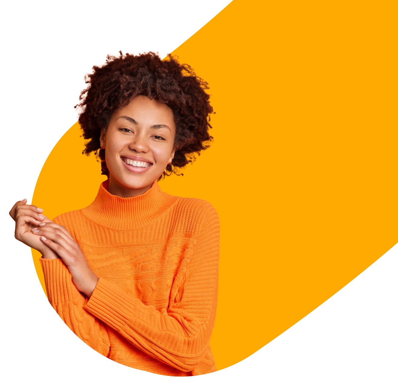 A woman with curly hair smiles, wearing an orange sweater. She stands against a background with an orange and white geometric design.