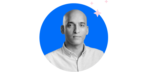 A person with a shaved head, wearing a light-colored shirt, is centered in front of a blue circular background with small sparkles in the upper right corner.