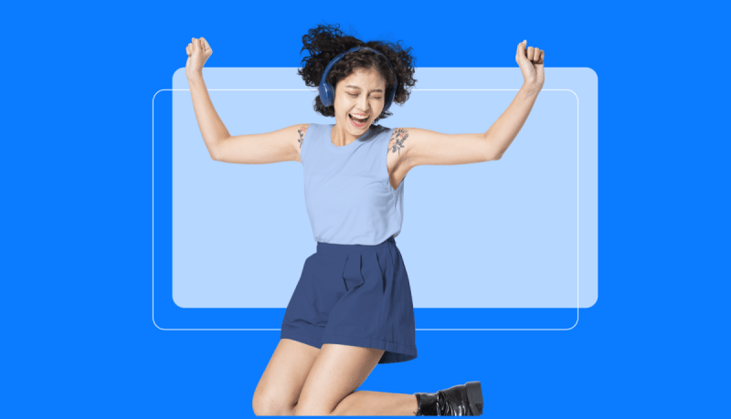 A person with curly hair, wearing headphones, a blue sleeveless top, and blue shorts, jumps with both arms raised against a blue background.